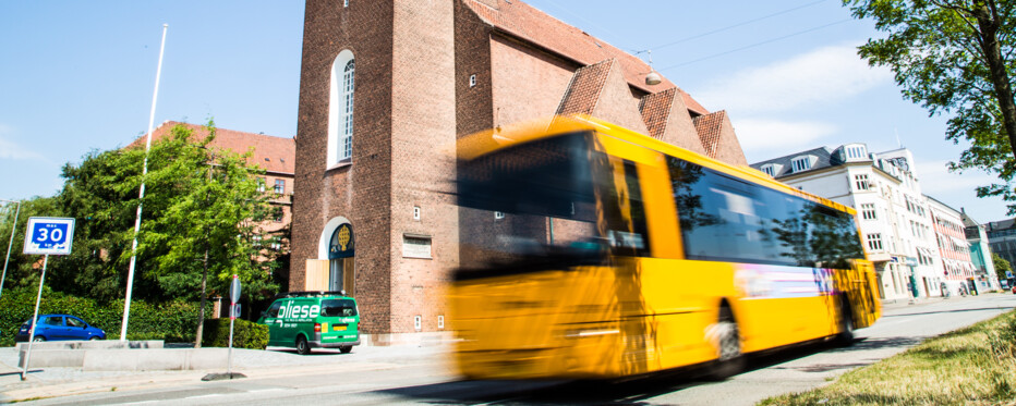 Taksigelseskirken set fra jagtvej med en gul bybus i fart