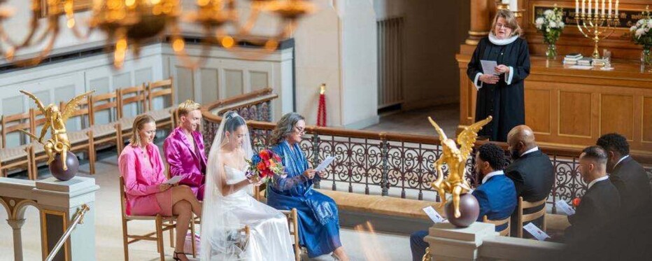 in front of the altar in a church, a wedding party is singing from the hymn book