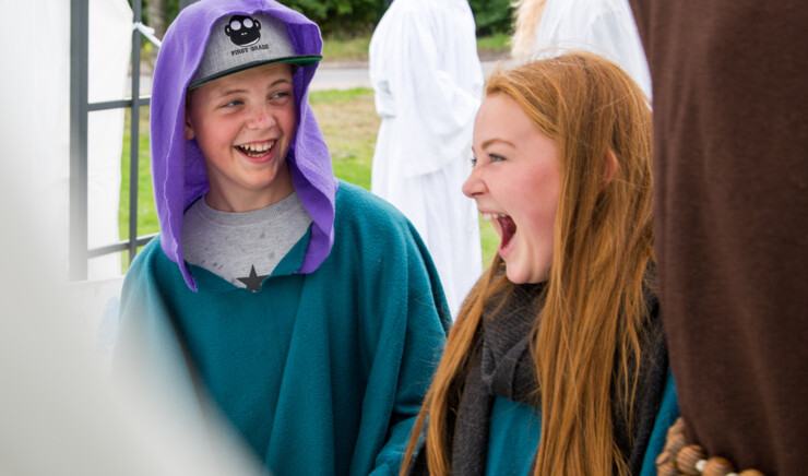 To børn i konfirmandalderen griner i kostume