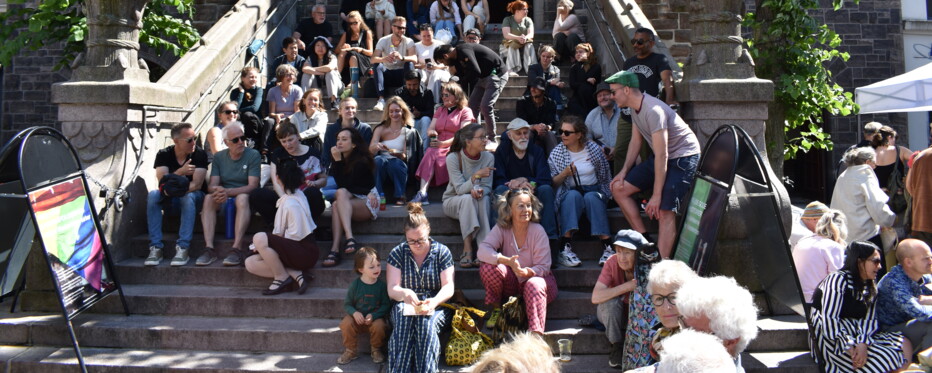 dozens of people sit on the sun kissed steps of Eliaskirken in copenhagen