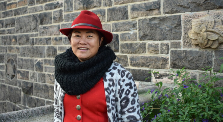 Diana stands in front of eliaskirken wearing a red hat and a big smile