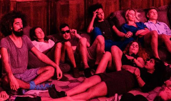 A crowd of young people relaxing on the floor of a church listening to music