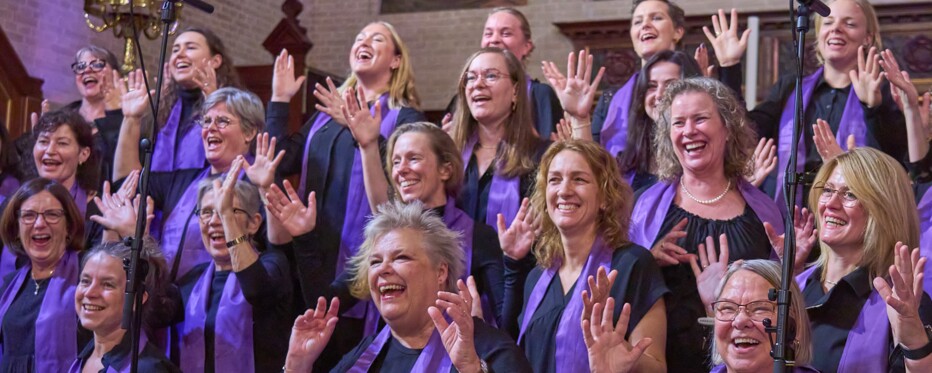 A gospel choir wearing purple scarf swing and sway to the music in a church