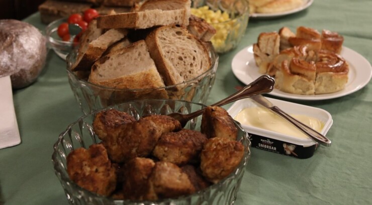 A decked table with a green table cloth presents Danish meat balls, vegan butter, bread and many other delicious dishes