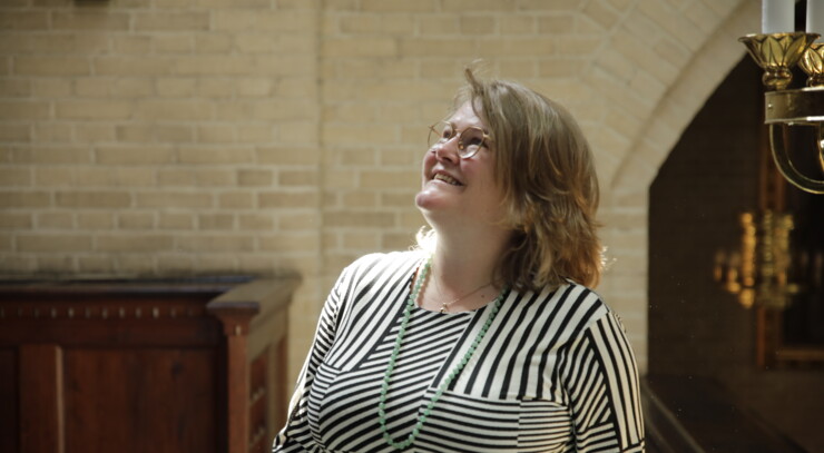 Pastor Maria, smiling, walks through Eliaskirken and looks up at the altar