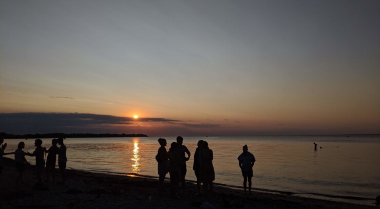 Foran en lys sommerhimmel anes silhouetterne af glade københavnere, der har fejret sankhansaften på stranden