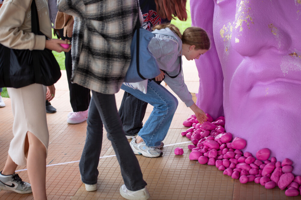 en gruppe unge lægger pink sten foran et pink Jesushoved