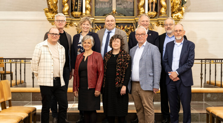 Ti biskopper står side om side i en kirke