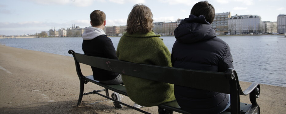 three people sitting on a bench in silence as an illustration of grief and loneliness