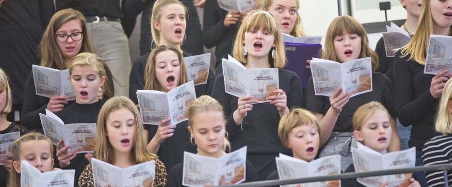 En flok syngende børn er sammen i et Kor i enghave Kirke